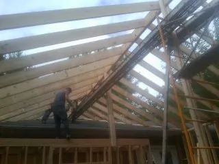 Rafters going up over a new addition with a worker on the wall in Elmwood Park